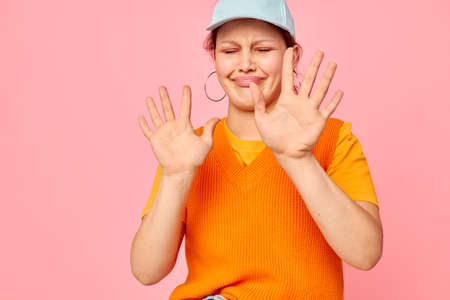 portrait of a young woman in an orange sweater in blue caps hand gesture isolated backgroundの写真素材