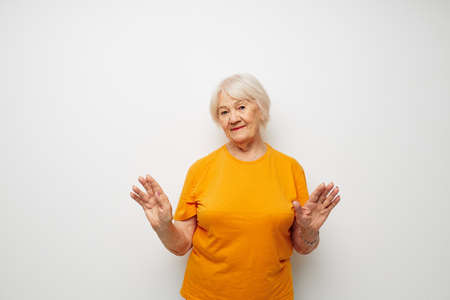 Photo of retired old lady in a yellow t-shirt posing light background