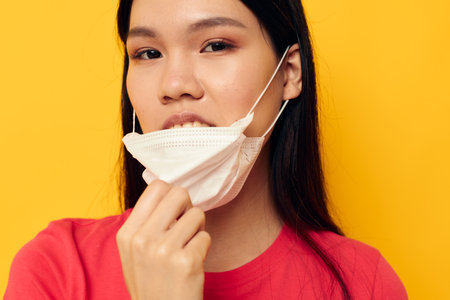Portrait Asian beautiful young woman posing medical mask close-up isolated background unalteredの写真素材