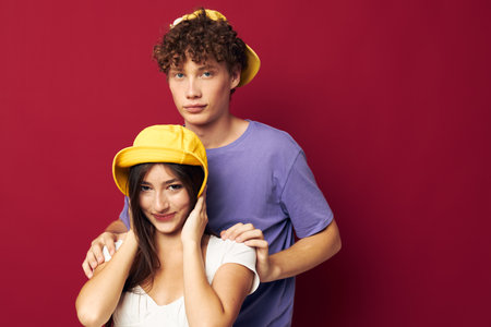 young man and girl in colorful t-shirts stylish clothes hats red background