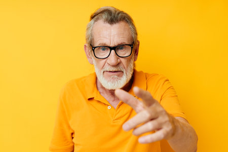 Portrait of happy senior man wearing glasses yellow shirt posing unaltered