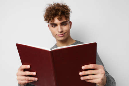 cute guy with curly hair with a book in his hands trainingの写真素材