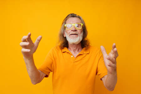 Portrait of happy senior man hand gestures emotions yellow glasses isolated backgroundの写真素材
