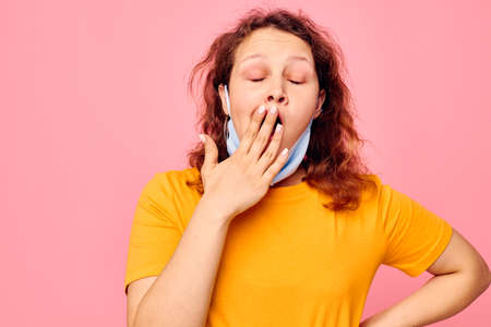 pretty girl in a yellow t-shirt medical mask protection pink background unaltered