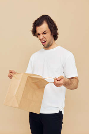 Cheerful man paper grocery bag posing isolated backgroundの写真素材
