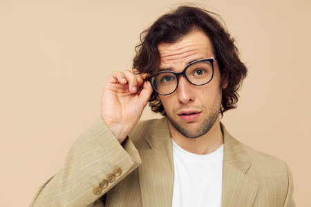 Cheerful man in a suit posing emotions wear glasses beige background