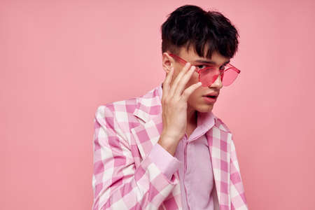 portrait of a young man pink glasses checkered jacket fashion posing pink background unalteredの写真素材