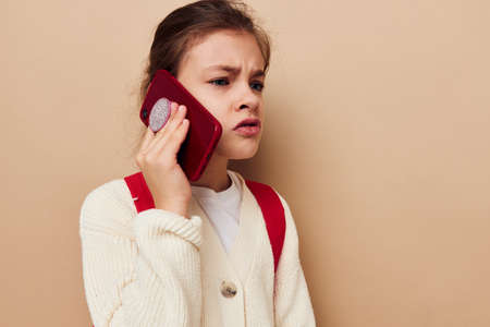 Portrait of happy smiling child girl schoolgirl backpack phone in hand childhood unalteredの写真素材