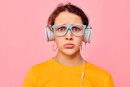 portrait of a young woman wearing headphones blue glasses close-up emotions cropped view unalteredの写真素材