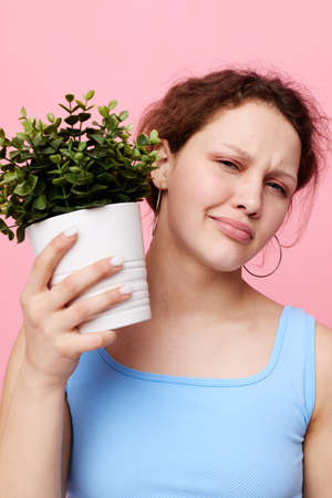 portrait of a young woman holding a pot with a flower isolated backgrounds unalteredの写真素材