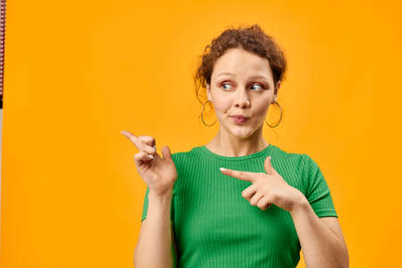cheerful cute girl with earrings green t-shirts yellow backgroundの写真素材