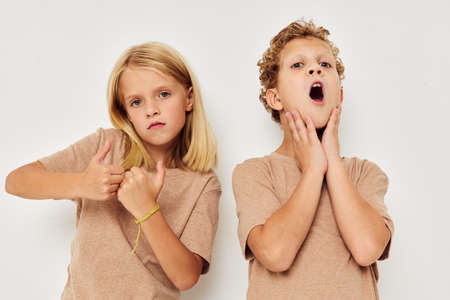 Portrait of cute children gesticulate with their hands together light backgroundの写真素材