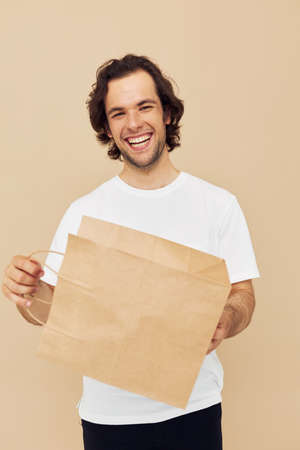 Cheerful man in a white T-shirt with paper bag Lifestyle unalteredの写真素材