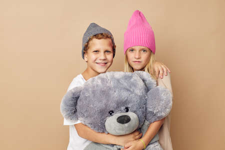 Little boy and girl in hats with a teddy bear friendship Lifestyle unaltered