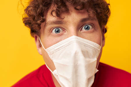 guy with red curly hair wearing a red t-shirt medical mask on the face posing Lifestyle unalteredの写真素材