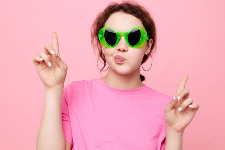 young woman in a pink T-shirt green glasses Youth fashion isolated background