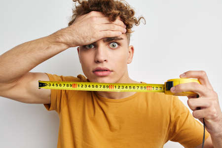 kinky guy measuring tape measure in yellow t-shirt light backgroundの写真素材
