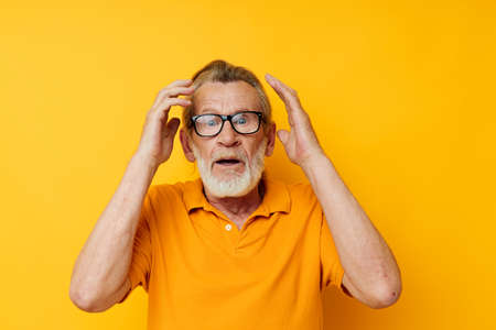 Portrait elderly man wearing glasses yellow shirt posing monochrome shotの写真素材