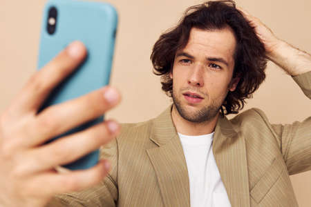 man with a phone in hand beige suit elegant style isolated background