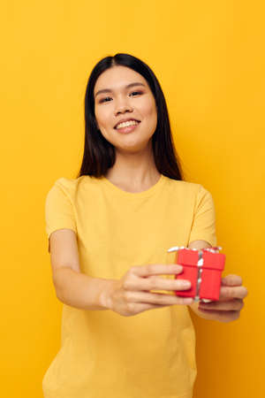 Charming young Asian woman in a yellow t-shirt holiday gift emotions studio model unalteredの写真素材