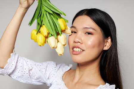 Portrait Asian beautiful young woman with a bouquet of flowers smile close-up light background unalteredの写真素材