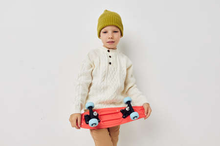 cute girl in hats with a skateboard in their hands light backgroundの写真素材