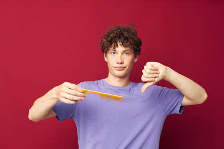 guy with red curly hair in purple t-shirts with a comb isolated background