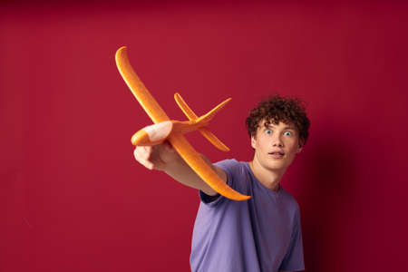 A young man with toy airplane entertainment red background unalteredの写真素材