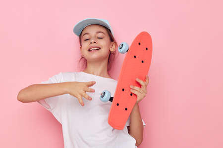 Portrait of happy smiling child girl cap in white t-shirt skateboard childhood unaltered