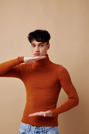 A young man posing in brown sweater self confidence fashion light background unalteredの写真素材