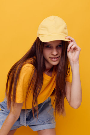 photo pretty woman posing in a yellow T-shirt and cap isolated backgroundの写真素材