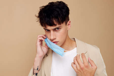 handsome guy a man in a light jacket medical mask light background unalteredの写真素材