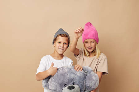 Portrait of cute children in hats with a teddy bear friendship isolated backgroundの写真素材