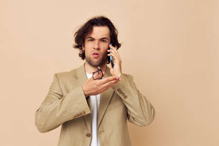 Attractive man communication by phone beige suit elegant style Lifestyle unalteredの写真素材
