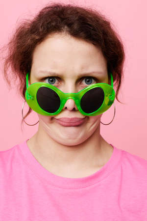 Young woman with green glasses decoration gesture with his hands pink backgroundの写真素材