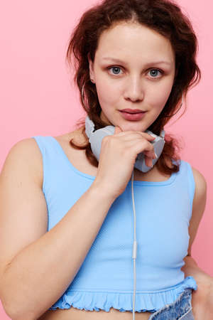 young woman teenager wearing headphones music entertainment pink background unaltered