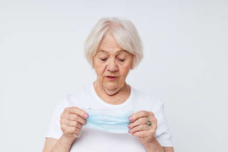 elderly woman medical mask in hand safety light background