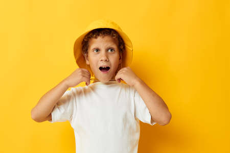 boy in white t-shirt yellow hat posing emotionsの写真素材