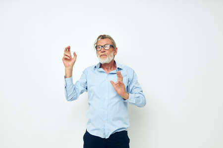 Senior grey-haired man in shirt and glasses posing emotions light backgroundの写真素材