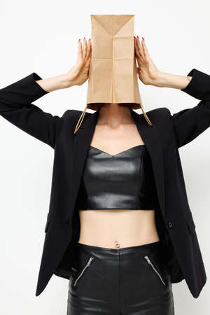attractive woman in a leather suit black jacket with a bag on his head isolated backgroundの写真素材