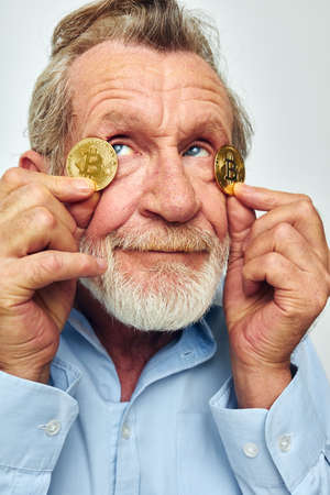 Portrait of happy senior man in a blue shirt bitcoins on the face cropped viewの写真素材