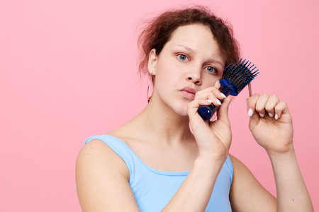 portrait of a woman dislike comb on hair emotion pink color background unaltered
