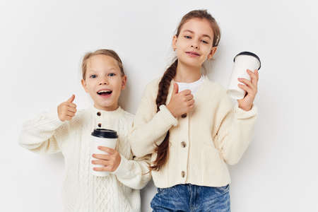 two little girls friends with glasses in their handsの写真素材