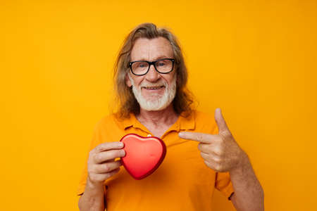 Senior grey-haired man red heart gift emotions yellow glasses cropped viewの写真素材