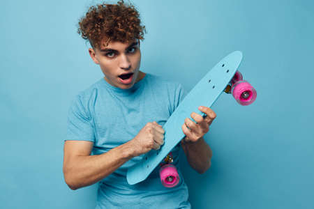 Attractive man blue skateboard in hand isolated backgroundの写真素材