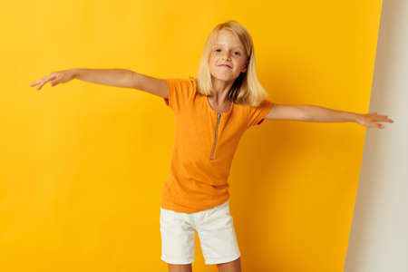 Little girl smile hand gestures posing casual wear fun yellow background unaltered