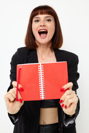 beautiful woman writing in a notebook black jacket isolated backgroundの写真素材