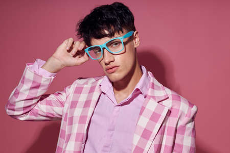 A young man fashionable glasses pink blazer posing studio pink background unaltered