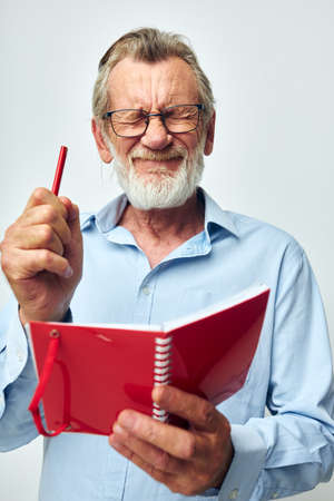 Portrait of happy senior man red notepad writing light background