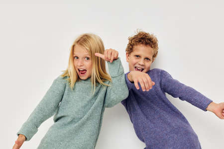 Portrait of cute children in multi-colored sweaters posing for fun light backgroundの写真素材